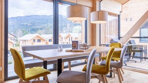 A modern wooden interior with large windows, a dining table, and chairs. - Lovely Penthouse With Sauna (Sankt Georgen am Kreischberg)