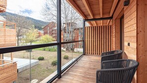 A wooden deck with a glass balustrade, two wicker chairs, and a view of a mountainous landscape. - Lovely Penthouse With Sauna (Sankt Georgen am Kreischberg)