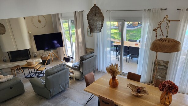 Uma sala de estar moderna com sofá, mesa de jantar com cadeiras, televisão e lareira.