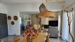 Uma sala de estar moderna com uma mesa de jantar de madeira, sofás e uma televisão.