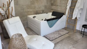 Um banheiro moderno com uma banheira grande, uma cadeira branca, uma cesta de palha e um porta-toalhas.