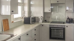 A compact kitchen with white cabinets, a microwave, a kettle, a toaster, and an oven. - 3 bedroom accommodation in Pagham, near Bognor Regis (Pagham, near Bognor Regis)