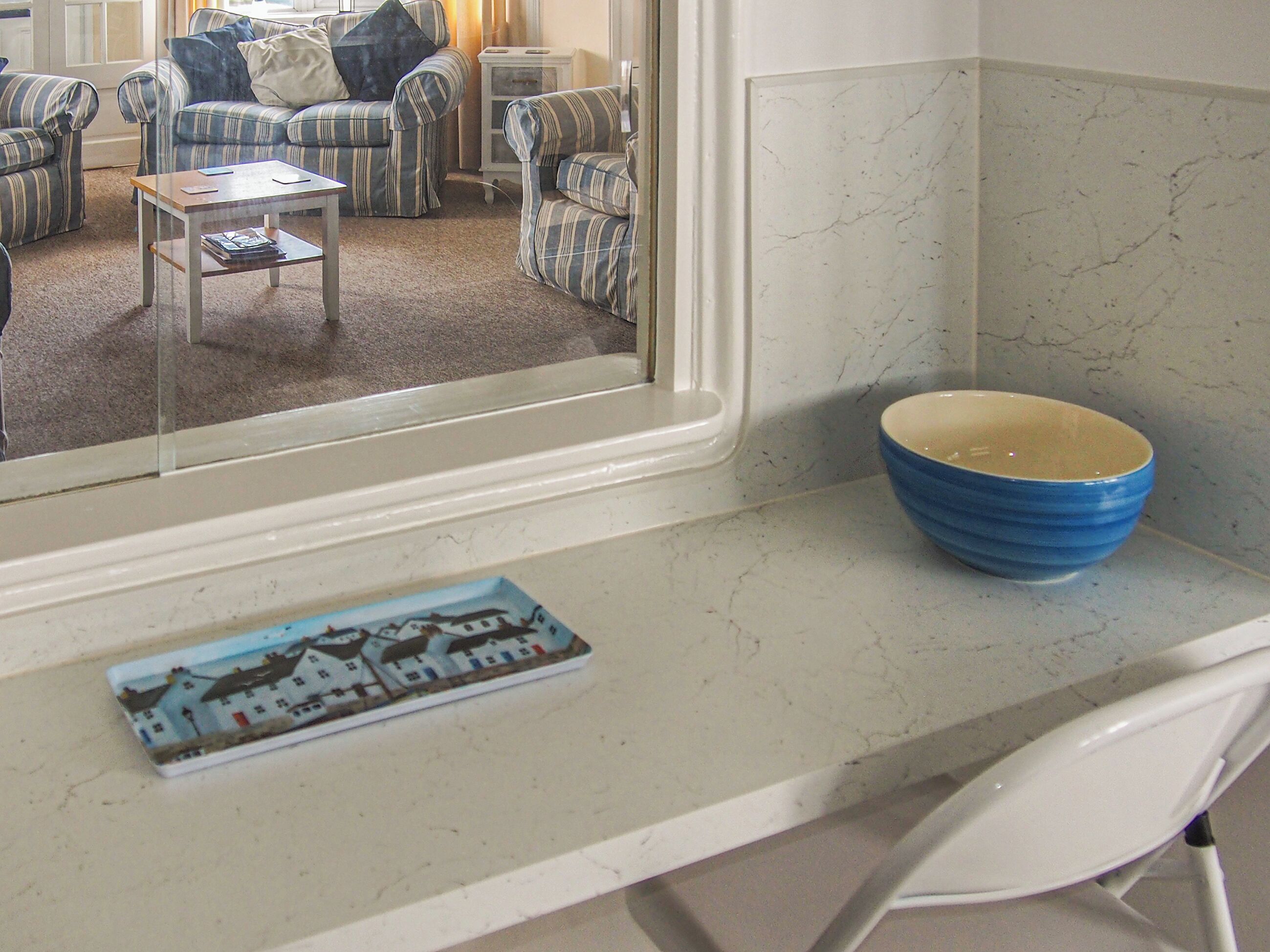A kitchen with a marble countertop, a blue bowl, and a small decorative plate.