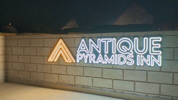 Um letreiro de neon para 'Antique Pyramids Inn' em uma parede de tijolos.