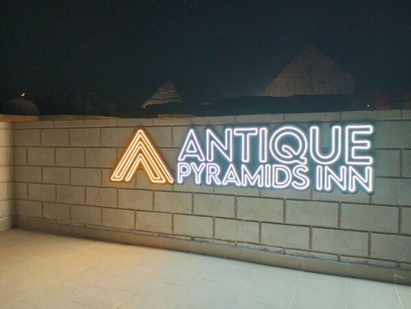 A neon sign for 'Antique Pyramids Inn' on a brick wall. - Antique Pyramids Inn (Giza)