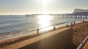 A beach with a pier extending into the water, people walking along the shore, and a clear sky. - 1 bedroom accommodation in Bishopsteignton (Bishopsteignton)