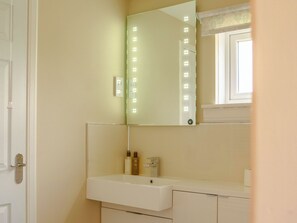 A bathroom with a white sink, a mirror with lights, and a window with a curtain. - 2 bedroom accommodation in Methven, near Perth (Methven, near Perth)