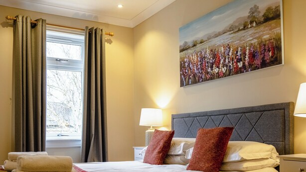 A hotel room with a bed, two bedside lamps, a painting on the wall, and a window with curtains. - 2 bedroom accommodation in Methven, near Perth (Methven, near Perth)