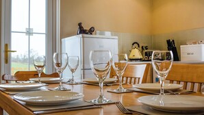 A dining table set with plates, glasses, and cutlery in a kitchen with a refrigerator and a kettle. - 2 bedroom accommodation in Methven, near Perth (Methven, near Perth)