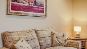 A plaid sofa with two pillows, a framed painting above, and a bedside table with a lamp. - 2 bedroom accommodation in Methven, near Perth (Methven, near Perth)