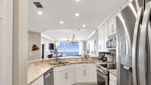Una cocina moderna con armarios blancos, electrodomésticos de acero inoxidable y vistas al exterior.