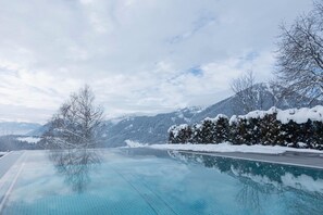 Ein Infinity-Pool mit freiem Blick auf schneebedeckte Berge und einen See.