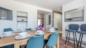 A dining area with a wooden table set for four, blue chairs, and a bar area with stools. - 5 bedroom accommodation in Eglwyswrw (Eglwyswrw)