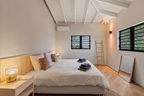A bedroom with a bed, bedside table, lamp, window, and ladder.