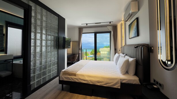 Une chambre d’hôtel moderne avec un grand lit, un bureau et une vue sur la mer.