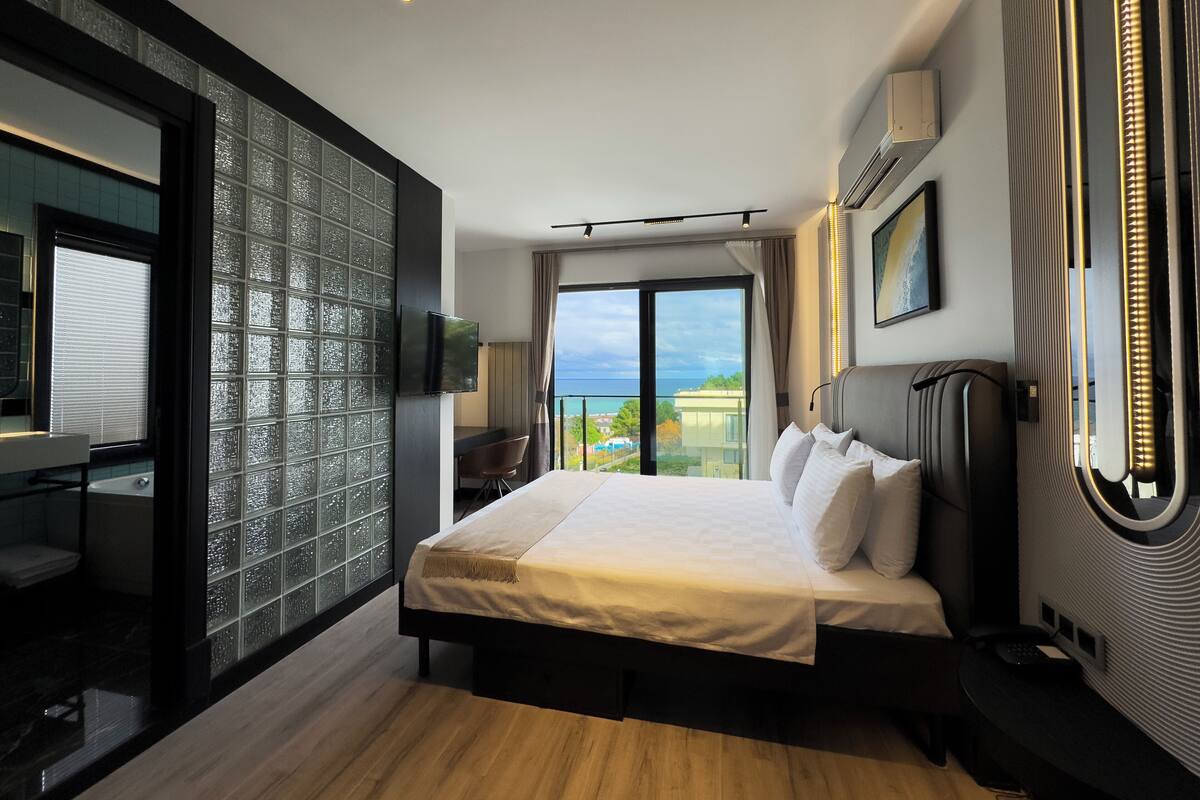 Ein modernes Hotelzimmer mit einem großen Bett, einem Schreibtisch und Meerblick.