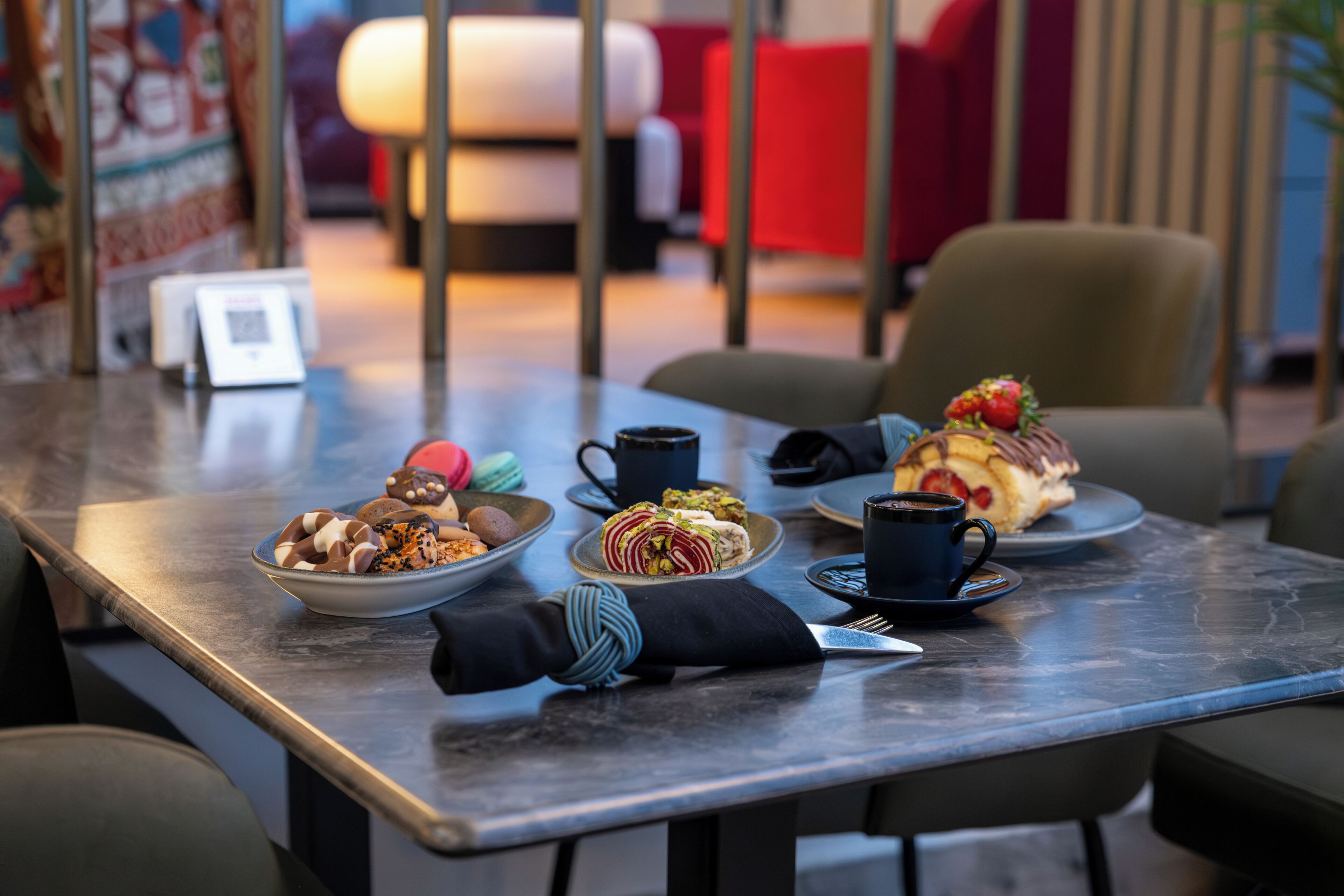 Una mesa con diversos postres, una taza y una servilleta.