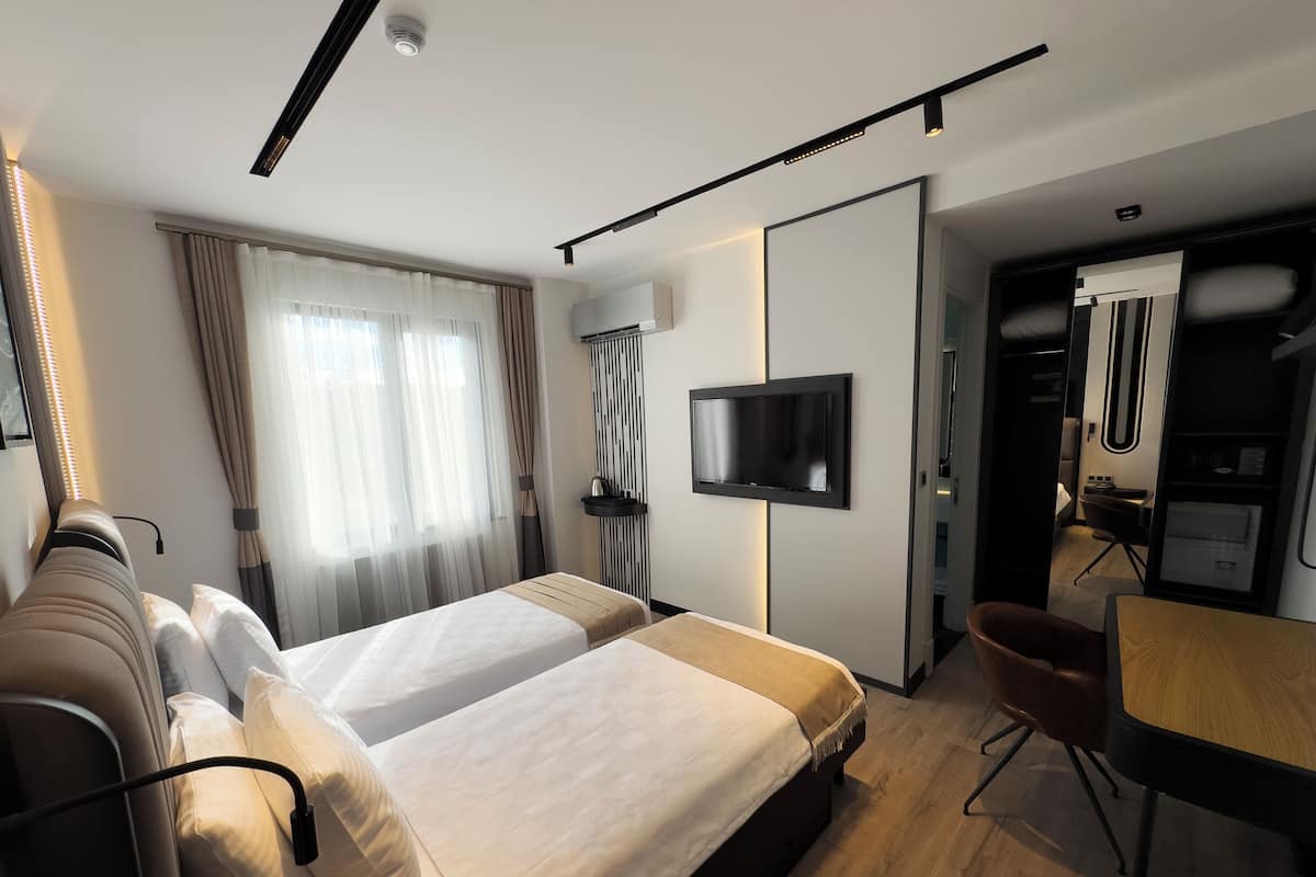 Ein modernes Hotelzimmer mit einem großen Bett, einem Schreibtisch, einem Fernseher und einem Kleiderschrank.