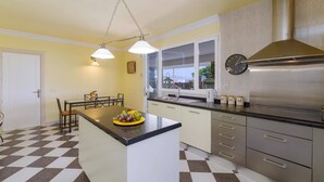 A kitchen with a central island, a stainless steel range hood, and a window with a view.