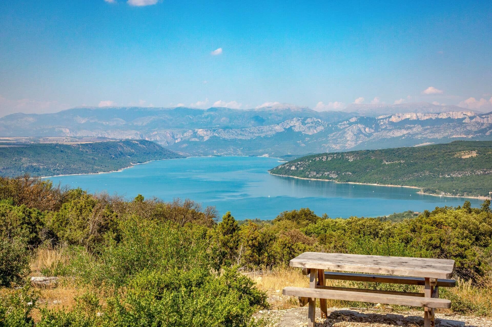 A wooden bench overlooking a lake with mountains in the background.
