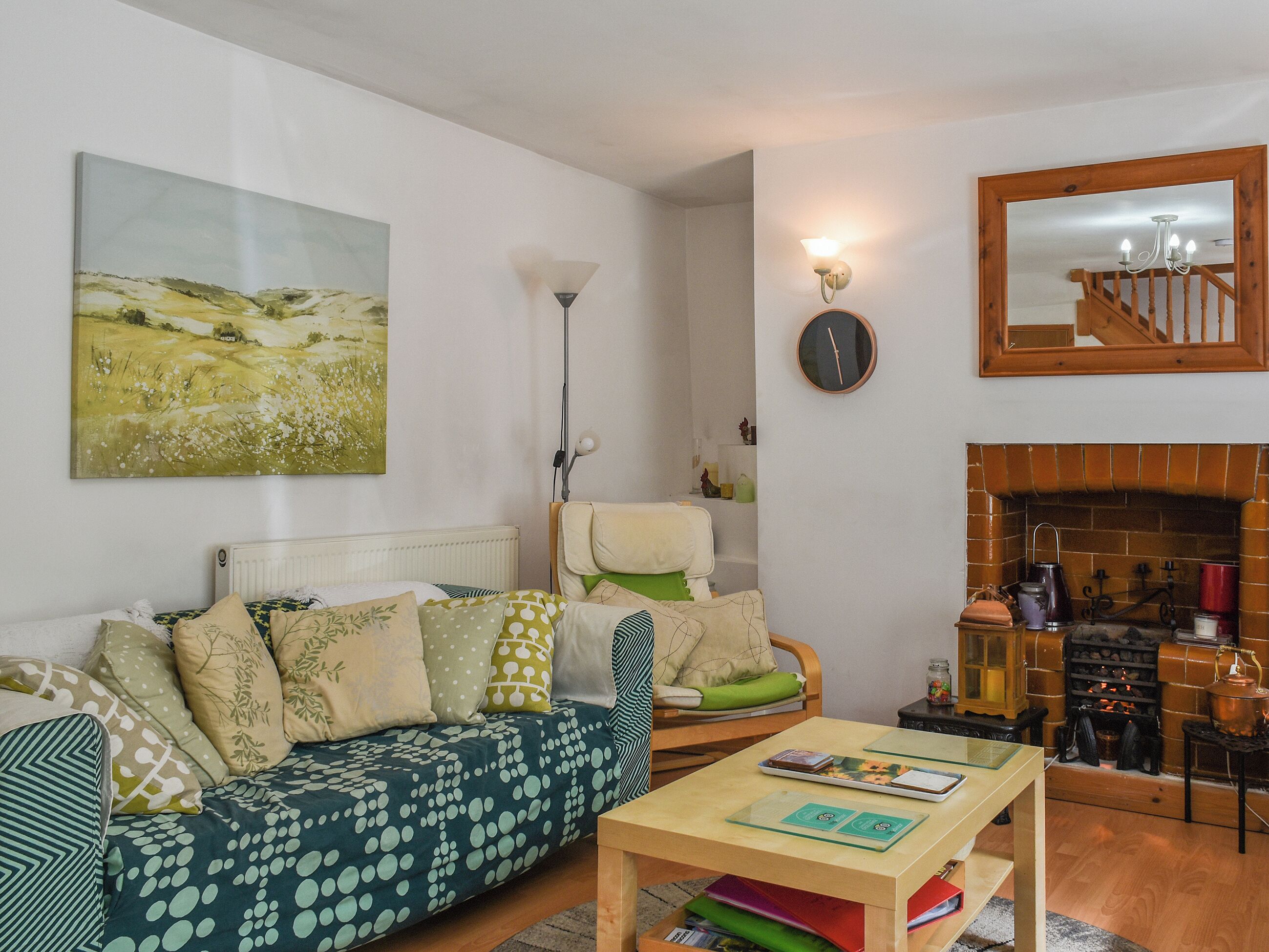 A cozy living room with a sofa, a coffee table, a fireplace, and a painting on the wall.
