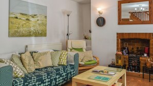 Ein gemütliches Wohnzimmer mit einer Couch, einem Couchtisch, einem Kamin und einem Bild an der Wand.