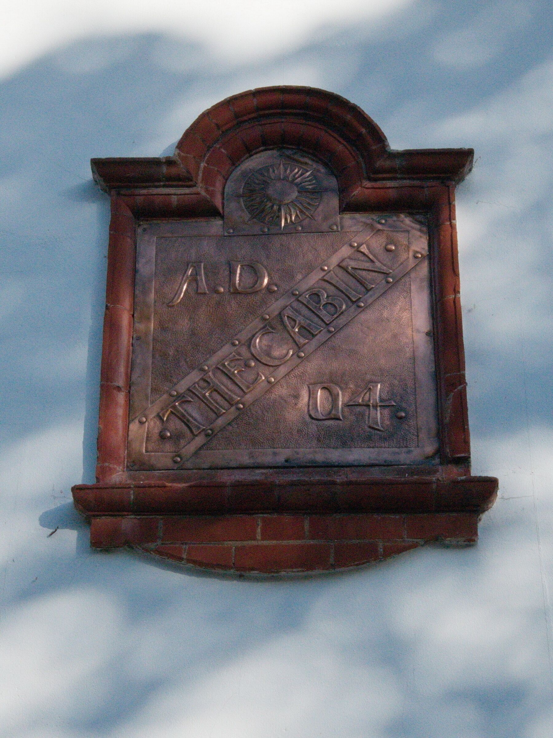 A plaque with the inscription "A.D. CABIN 04" mounted on a brick wall.