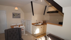 Un espacio habitable compacto con comedor, kitchenette y una sala de estar con dos sofás.