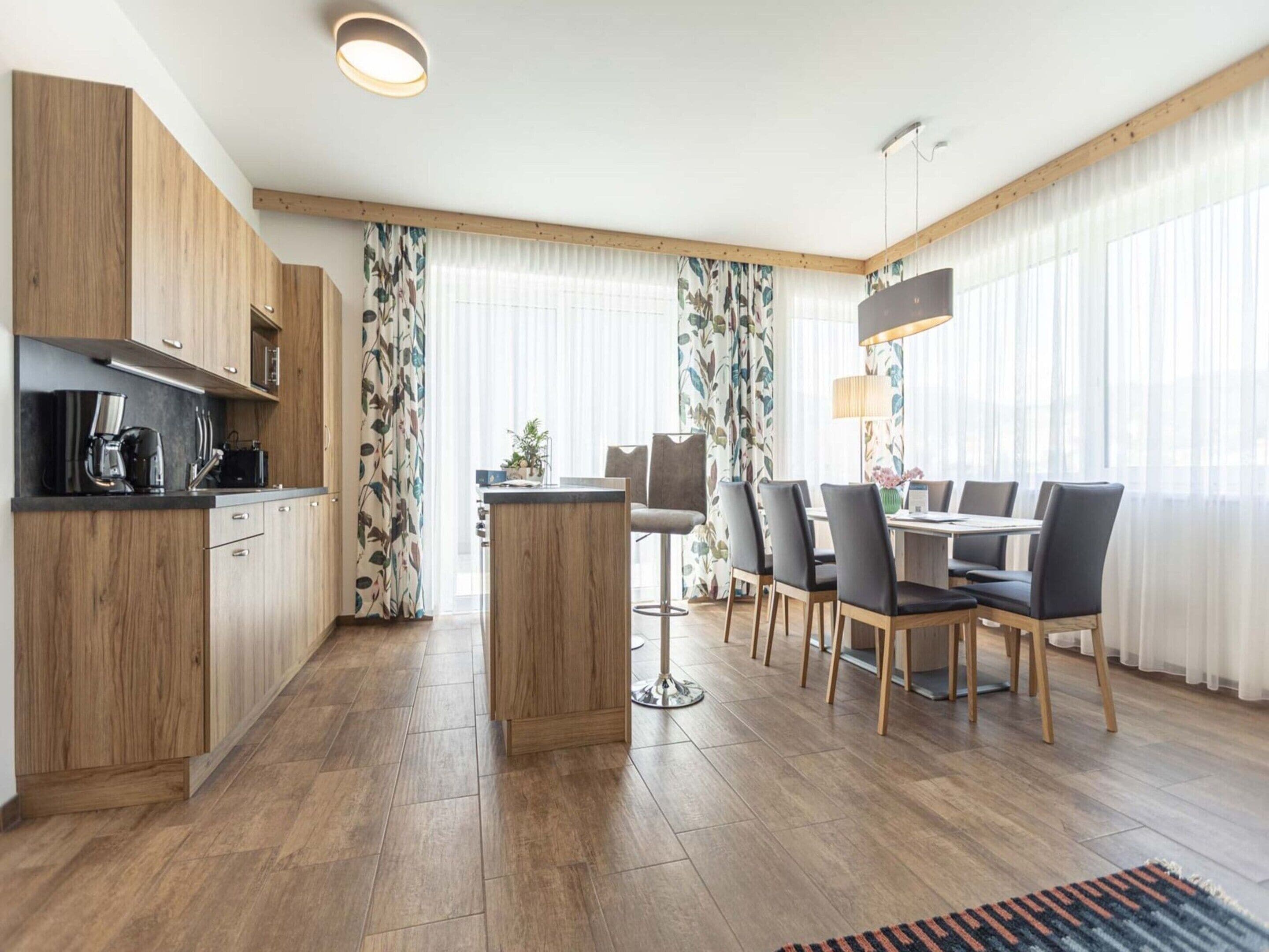 Eine moderne Küche mit Holzausstattung, einer Kaffeemaschine und einem Essbereich mit Tisch und Stühlen.
