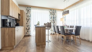 A modern kitchen with wooden cabinets, a coffee machine, and a dining area with a table and chairs.