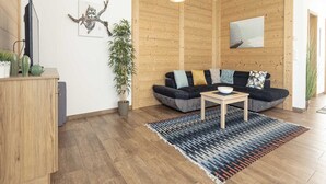 A modern living room with a dark sofa, a coffee table, a potted plant, and a wooden cabinet.