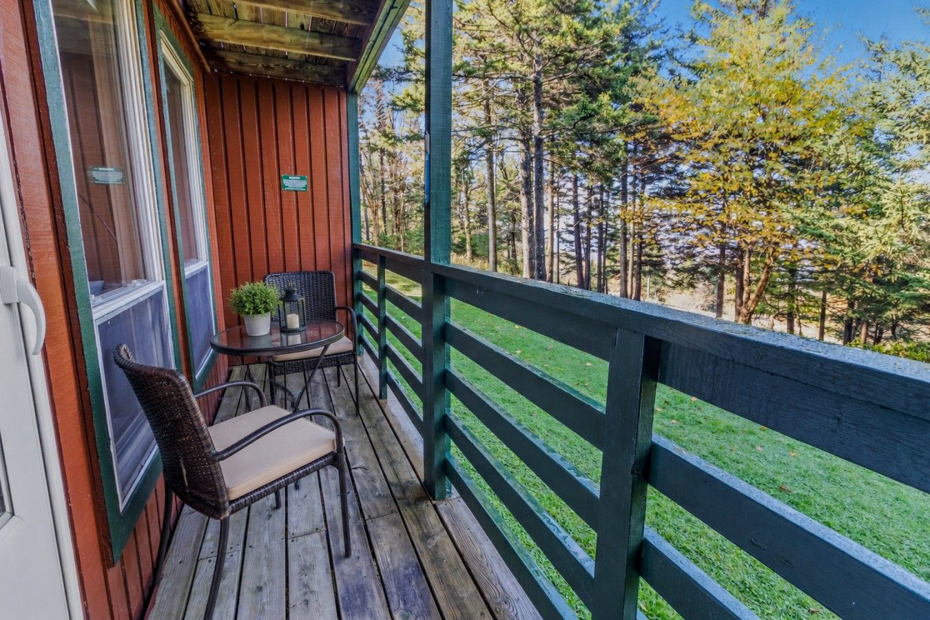 A wooden deck with a table and chairs, overlooking a forested area.