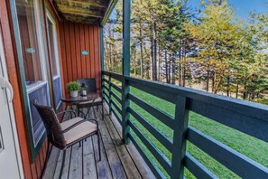 Une terrasse en bois avec une table et des chaises, donnant sur une zone boisée.