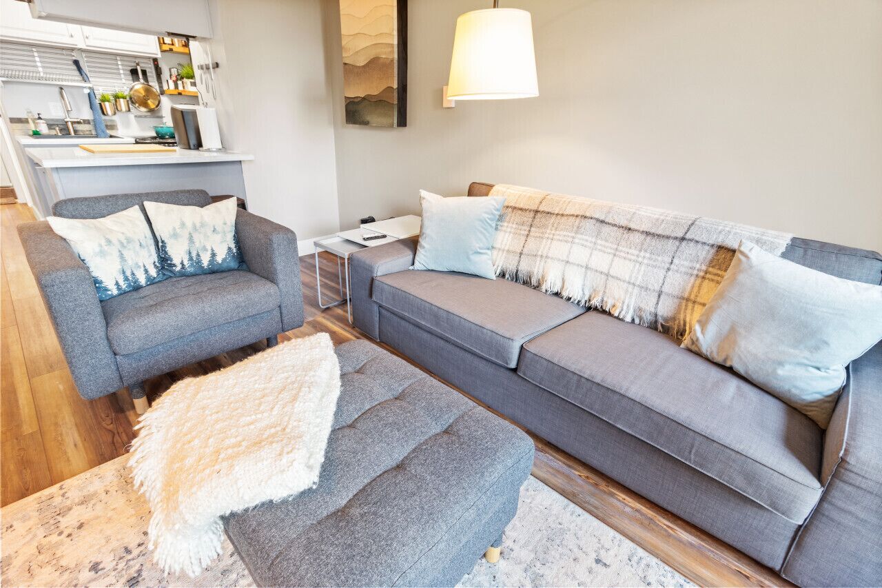 A modern living room with a grey sofa, a matching armchair, and a small side table.