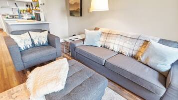 A modern living room with a grey sofa, a matching armchair, and a small side table.