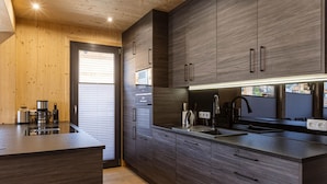 Een moderne keuken met donkere houten kastjes, een zwart aanrecht en een ingebouwde oven.