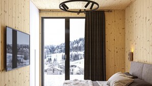 Een moderne kamer met houten wanden en plafond, een groot raam met uitzicht op een besneeerd landschap, een bank met kussens, en een wandgemonteerde flatscreen-tv.
