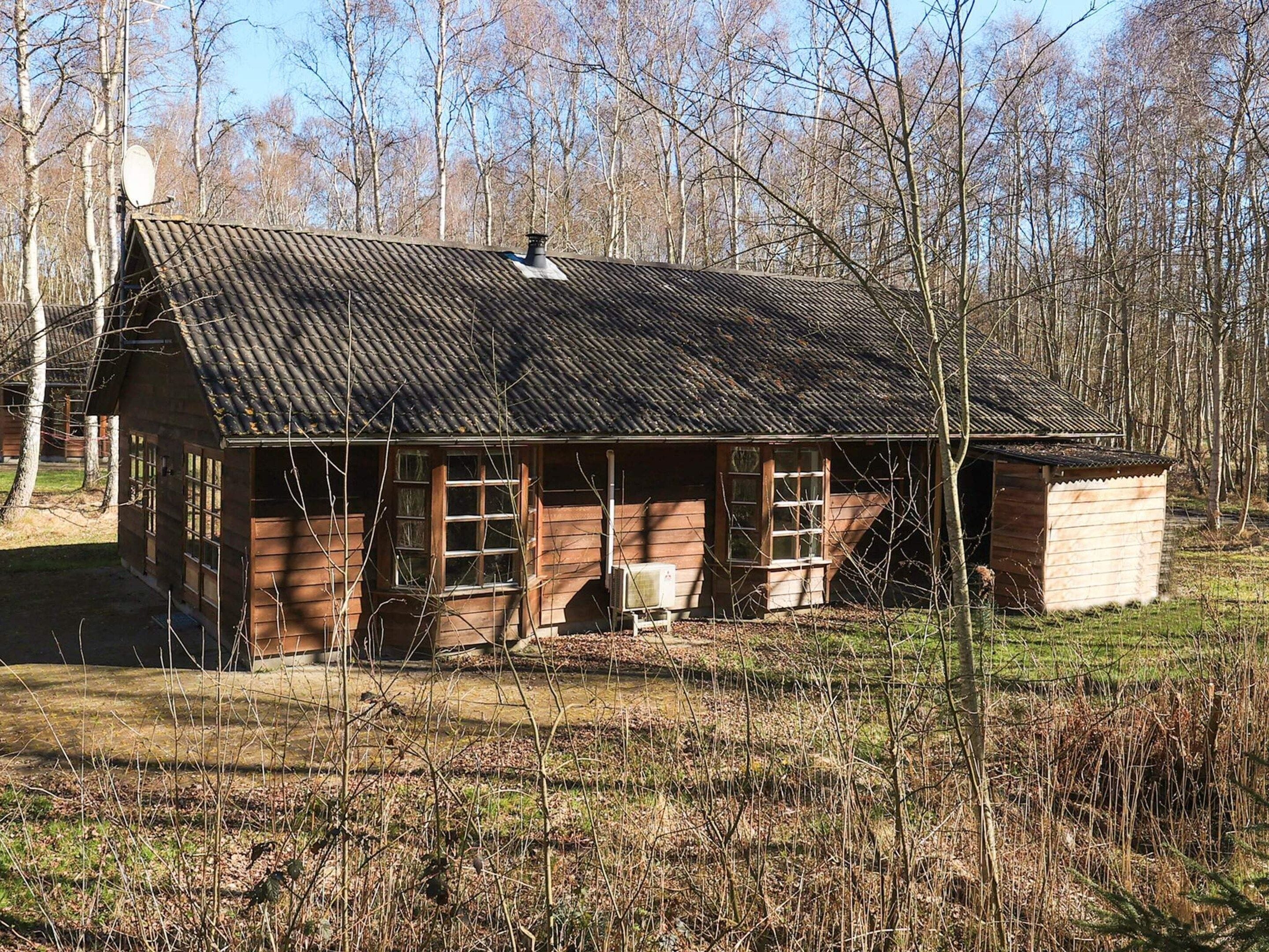 A rustic wooden cabin with a sloped roof, large windows, and a chimney.