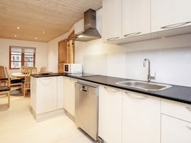 Una cocina moderna con armarios blancos, un lavamanos de acero inoxidable y un microondas.