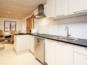 A modern kitchen with white cabinets, a stainless steel sink, and a microwave. - 6 Person Holiday Home in Laeso (Læsø)