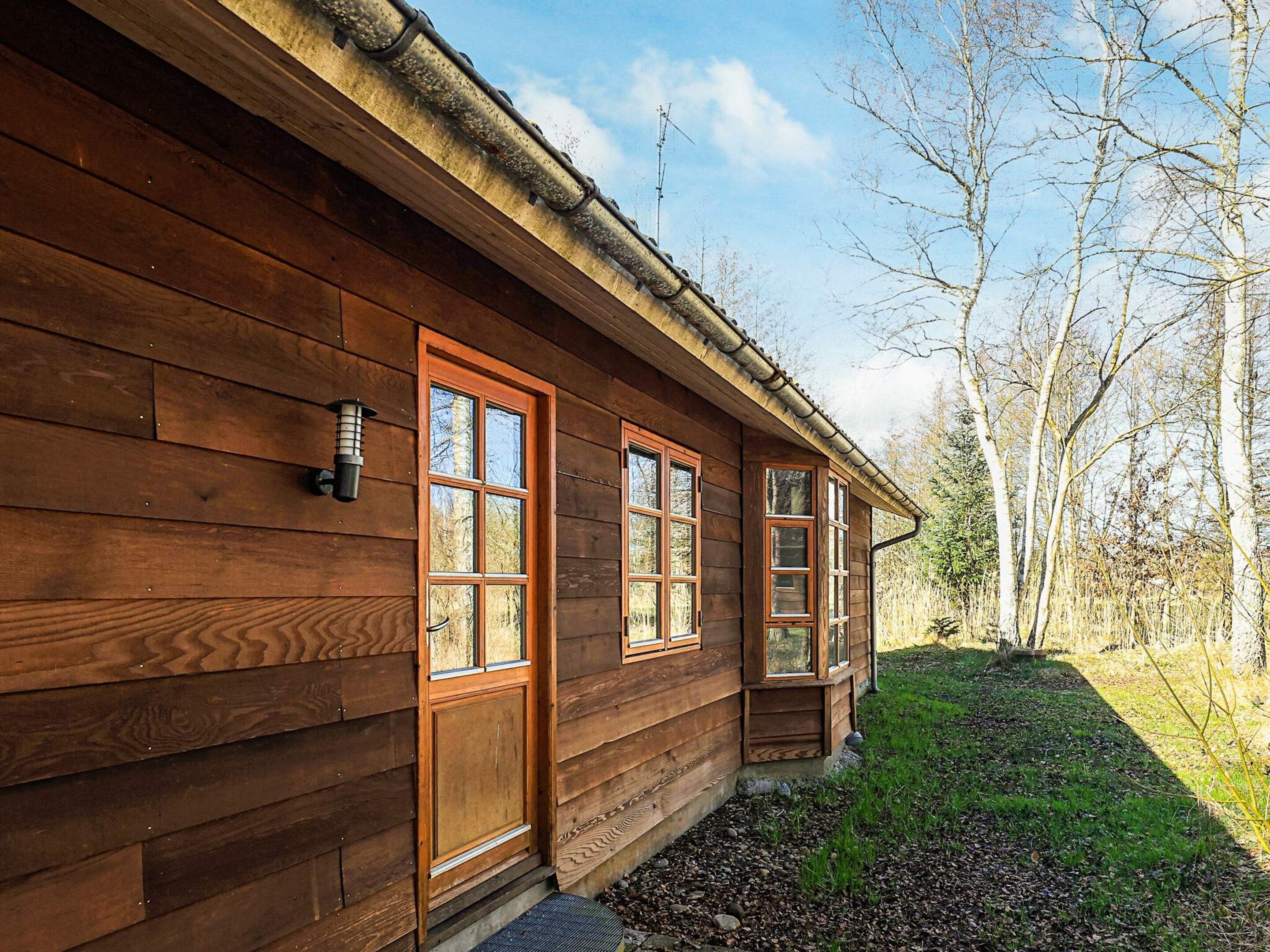 A wooden cabin with a front door, two windows, and a small porch area.