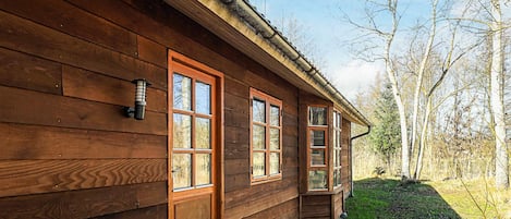 A wooden cabin with a front door, two windows, and a small porch area.