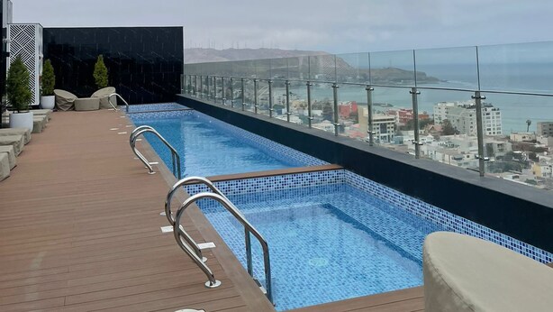 Piscina infinita no terraço com vista para a cidade e oceano.
