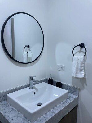 A bathroom with a white sink, a round mirror, and a towel rack. - Stylish1BR with Private Balcony in Barranco (Lima)