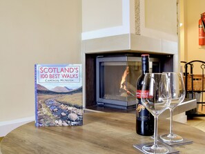 Un libro titulado 'Scotland's 100 Best Walks' sobre una mesa, una botella de vino 'Yellowtail Red Roo' y dos copas de vino.