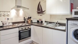 A modern kitchen with white cabinets, a stainless steel range hood, a built-in oven, a microwave, and a dishwasher. - The Snug, Lynmouth - UK41696 (Lynmouth)