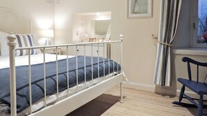 A bedroom with a bed, a bedside table, a chair, a window with curtains, and a wall-mounted artwork. - The Snug, Lynmouth - UK41696 (Lynmouth)