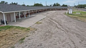 A motel with a row of rooms, a covered parking area, and a sign for 'West Lake Inn'. - Room 101 - Standard Queen - Sleeps 2 - West Lake Grandvue Inn (Downs)