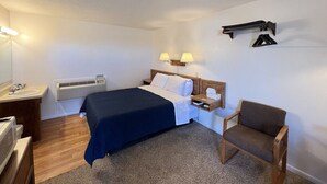 Une chambre d’hôtel équipée d’un lit, d’une table de chevet, d’une chaise et d’une lampe fixée au mur.