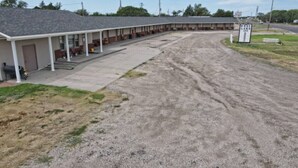 Un motel doté d’un parking couvert et d’une enseigne indiquant « West Lake Inn ».